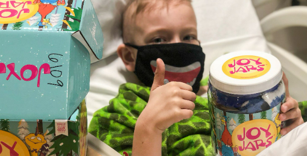 A child in the hospital giving a thumbs up with a NEGU JoyJar