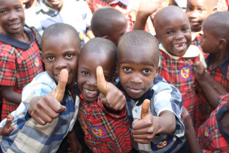 Schoolchildren in Uganda smiling and giving a thumbs up